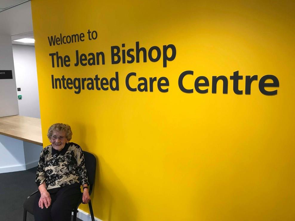 Older woman sat near care centre sign