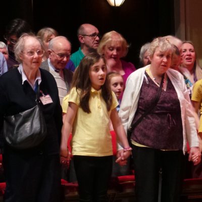 Group of school children and their parents singing