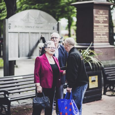 3 People are stood talking near a park