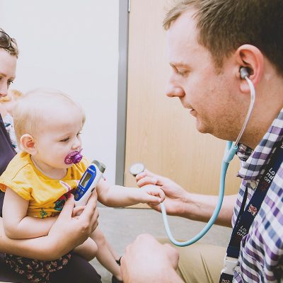 Doctor holding stethoscope to baby