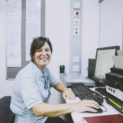 Woman sat at her desk smiling at camera