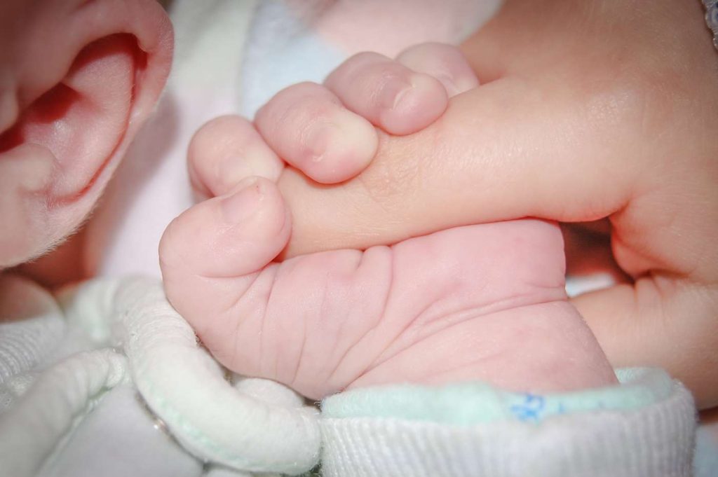 Baby holding parent's finger