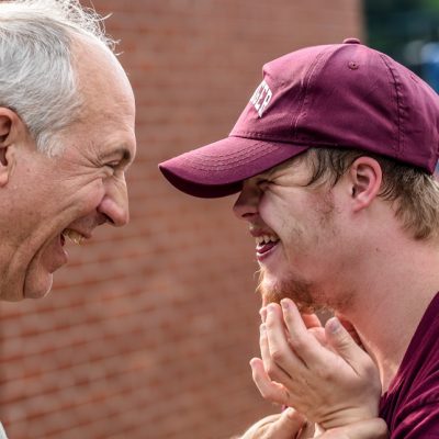 a young and a old man are stood laughing together